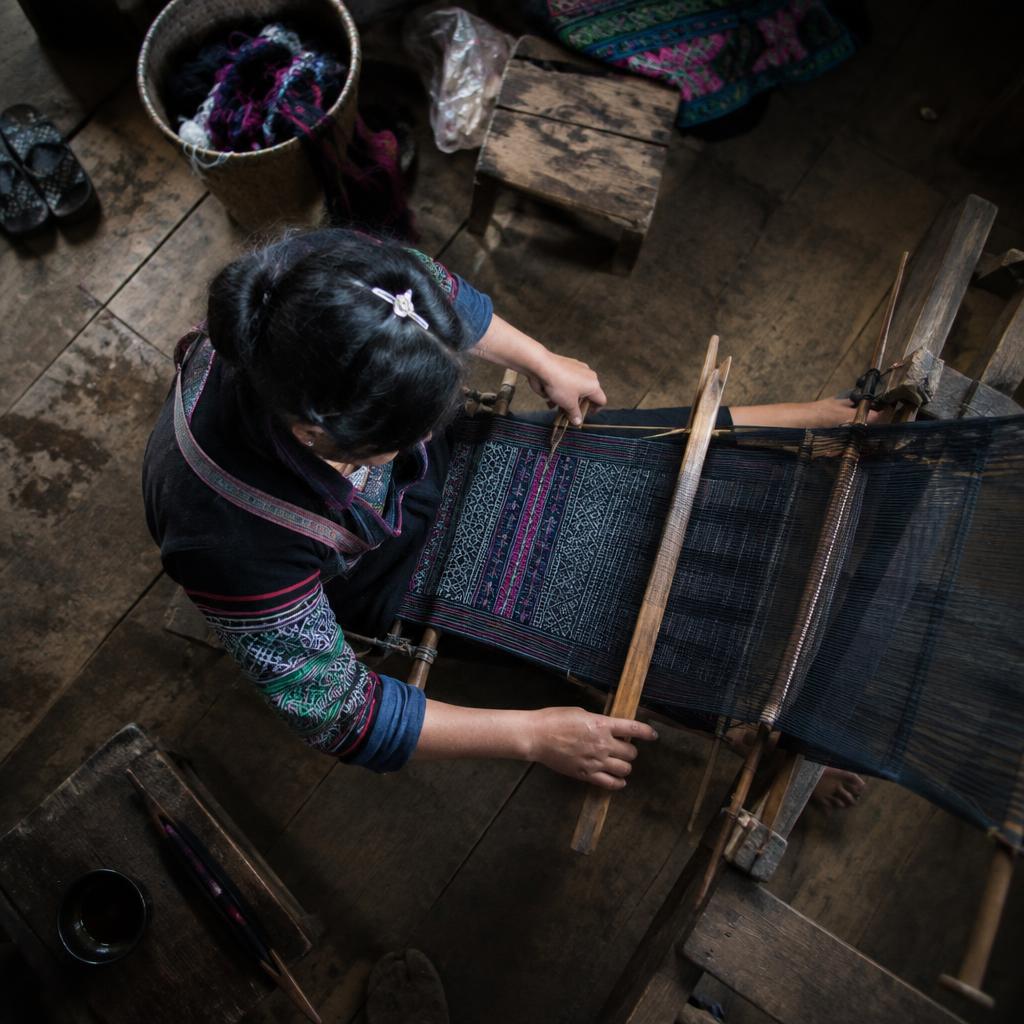 A local Hmong artisan demonstrating traditional weaving techniques in a Sapa village.